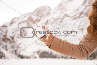 Closeup on throwing snowball woman among snow-capped mountains