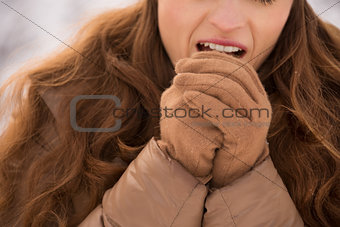 Closeup on woman warming hands with breathe in winter outdoors
