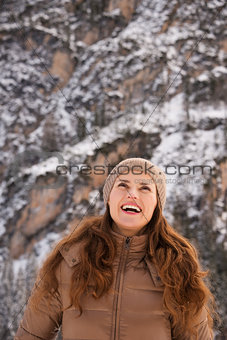 Smiling woman outdoors among snow-capped mountains looking up