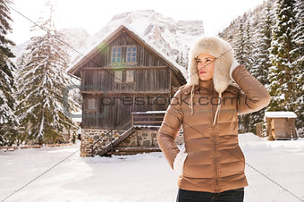 Woman looking into distance while standing near mountain house