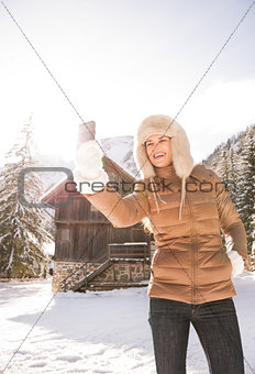 Woman standing in front of mountain house and taking selfie