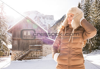 Woman standing near mountain house and looking into distance