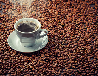 Hot aromatic coffee drink in the white cup with beans background
