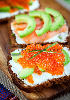 Appetizer with red caviar, avocado, salmon and creamcheese