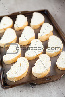 Slices of french bread loaf on baking tray
