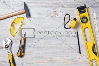 Top view of construction instruments and tools on wooden DIY workbench with copy space at center.