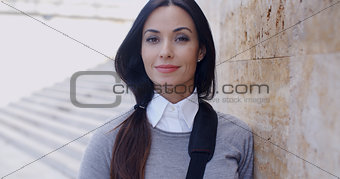 Confident young woman leaning against wall