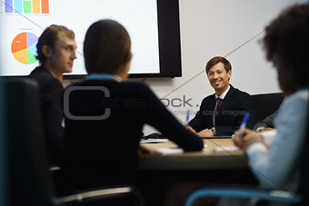 Business People In Office Meeting Room With Charts On TV