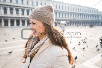 Portrait of happy young woman on Piazza San Marco among pigeons
