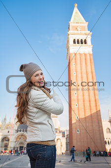 Happy young woman pointing on bell tower of St Mark's Basilica