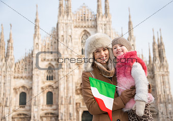 Happy mother and daughter with Italian flag standing near Duomo