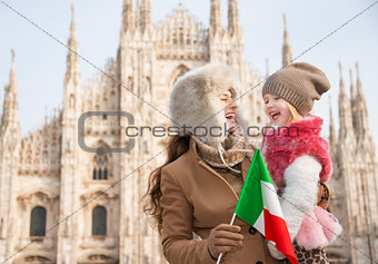 Smiling mother and daughter holding Italian flag near Duomo