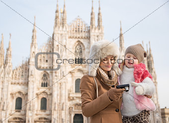 Mother and daughter looking on photos in camera near Duomo