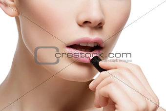 Closeup of beautiful girl applying pink lipstick