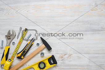 Top view of construction instruments and tools on wooden DIY workbench. with open space. Level, tape measure, wrench, hammer, cutter.