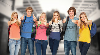 Composite image of smiling group giving a thumbs up as they wear backpacks