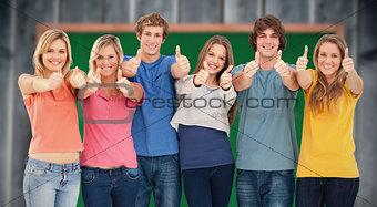 Composite image of six friends giving thumbs up as they smile