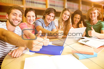 Composite image of college students gesturing thumbs up in library
