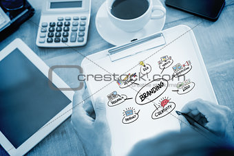 Composite image of man writing on clipboard on working desk