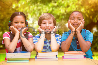 Composite image of cute pupils looking at camera in library