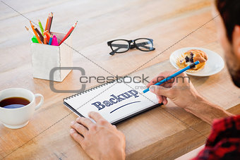 Testing against creative businessman writing notes on notebook