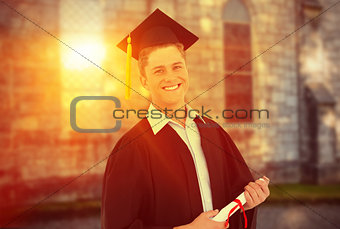 Composite image of a smiling man with a degree in hand as he looks at the camera