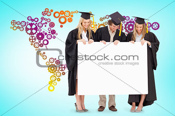 Composite image of three smiling students in graduate robe holding a blank sign