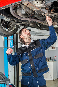 Mechanic checking the condition of a lifted car