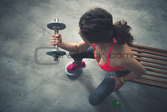 Seen from above fitness woman lifting dumbbell