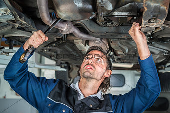 Mechanic repairing a lifted car wit