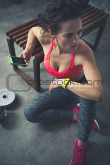 Fitness woman sitting in loft gym with cell phone