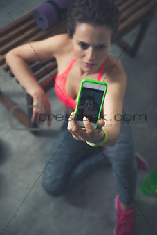 Closeup on fitness woman sitting in loft gym and taking selfies
