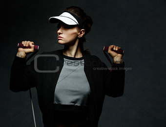 Fit woman workout with resistance band against dark background