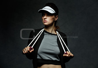 Young fit woman holding resistance band against dark background