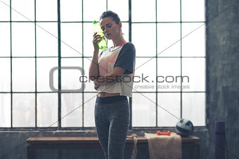 Woman in loft gym cooling after workout using bottle of water