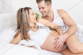 Delighted young parents in bed expecting a baby