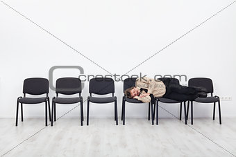 Office worker asleep on row of chairs