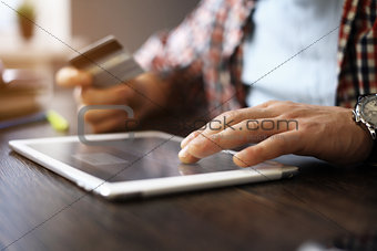 Man holding tablet pc and credit card indoor