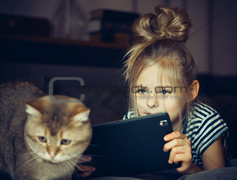 Beautiful girl holding a Tablet and looks at the cat