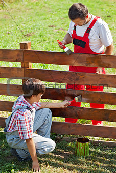 Father and son painting a garden fence