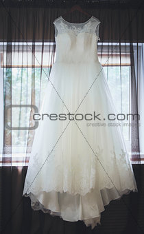 Wedding dress hanging in a window.