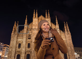 Happy woman with photo camera near Duomo in evening, Milan