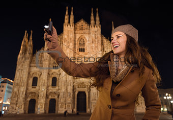 Smiling woman taking photos in front of Duomo in evening , Milan