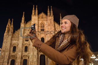 Woman with photo camera pointing on something near Duomo, Milan