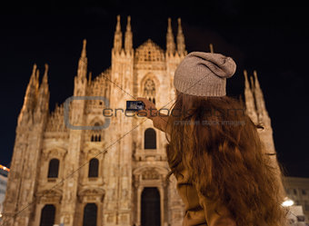 Young woman taking photo of Duomo in the evening, Milan