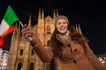 Smiling woman waving Italian flag near Duomo in evening, Milan