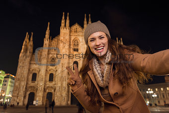 Woman showing victory gesture and taking selfie near Duomo