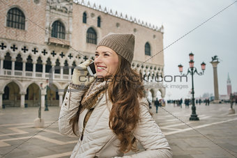 Smiling woman tourist talking cell phone on St. Mark's Square