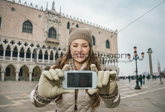 Woman tourist taking selfie with cell phone on St.Mark's Square