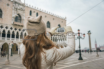 Seen from behind woman tourist taking photos on St.Mark's Square